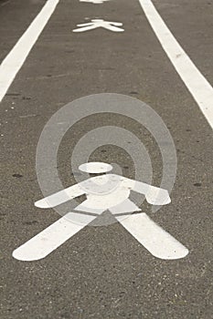 Walking man pavement sign painted white on concrete way