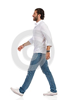 Walking Man In White Shirt, Jeans And Sneakers. Side View