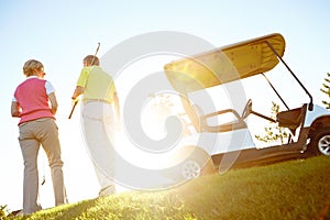 Walking off into the sunset. Rear view shot of an elderly couple walking to their golf cart.