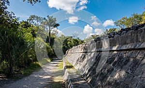 Walking path along ancient stone wall among Mayan ruins of Chichen Itza in Mexico