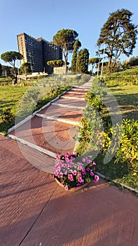 Walking path with flowers and surounding green and trees in EUR-Rome