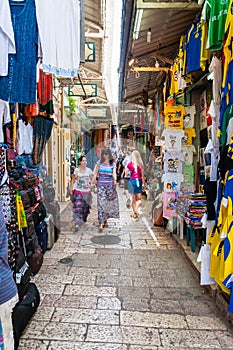 Walking people in ancient Old Town Market of Jerusalem full of shops with all kinds of touristic products like t-shirts, souvenirs