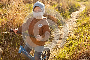 Walking during the quarantine. A small boy in a mask rides a Bicycle