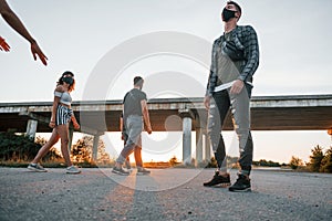 Walking on the road. Group of young cheerful friends having fun together. Party outdoors