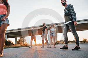 Walking on the road. Group of young cheerful friends having fun together. Party outdoors
