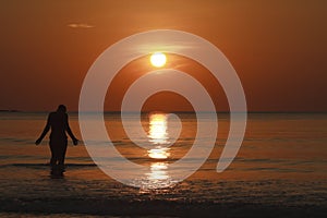 Walking into the sea at sunset