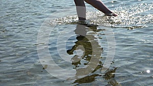 Walking in Shoal. Top view of barefoot man vacationer walking along the beach and sea waves washing his feet.