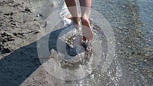 Walking in Shoal. Top view of barefoot man vacationer walking along the beach and sea waves washing his feet.