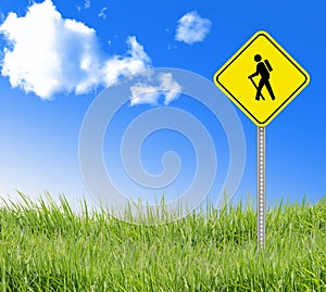 Walking sign on green grass and blue sky.
