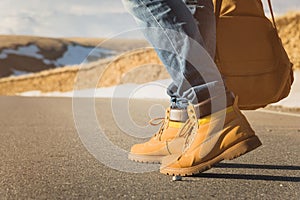 Walking on the summer sunset on the asphalt, men`s legs in yellow shoes and blue jeans go along the asphalt. Next to the