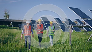 Walking to the camera happy group of investors and ecological engineer at photovoltaic solar farm they analysing the