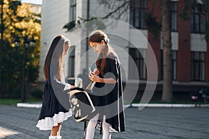 Walking together. Two schoolgirls is outside near school building