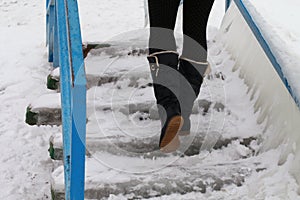 Walking up in a boots on an ice-bound stairs.