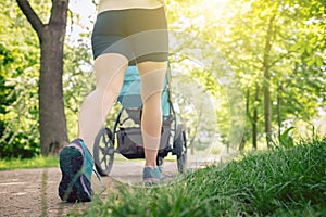 Walking woman with baby stroller enjoying summer in park