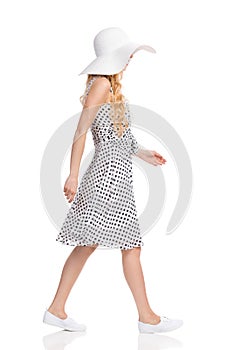 Walking Woman In White Dotted Dress, Sun Hat And Sneakers