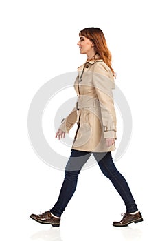 Walking Young Woman In Beige Coat, Jeans And Brown Shoes