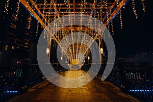 a walkway covered with christmas lights and lit up by street lamps