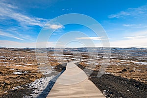 Walkway of gullfoss waterfall in Iceland surrounding by grass field with blue sky