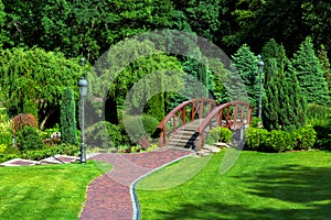 Walkway leading to a decorative wooden bridge over a pond.