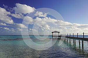 A walkway leads out to a dock over a tropical lagoon in the South Pacific