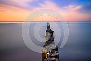 Walkway made of tree trunks in sea during sunset in Ostsee