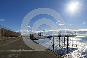 A walkway on the shore with a backlit jetty.