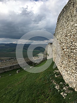 The wall of ancient fortress on a hill against the sky and clouds