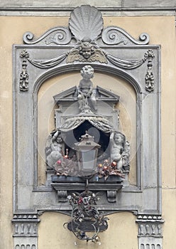 Wall art with cherubs surrounding a gothic lamp in Florence, Italy.