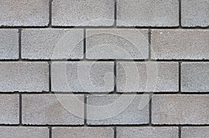 The wall of artificial brick made of concrete chips of gray color, interconnected with cement