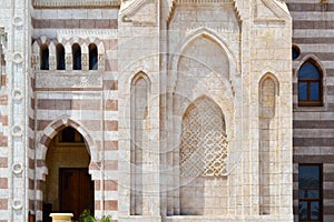 A wall with a beautiful texture of a Muslim Islamic Arab mosque made of white brick architecture with arches, tall towers, domes a