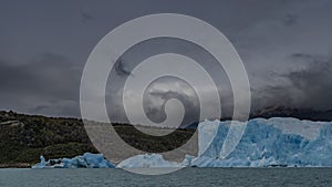 A wall of blue ice rises above a glacial lake.