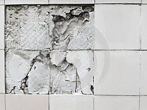 A wall with a broken off gray tile from the wall