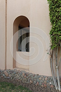 The wall of the building with the arch-shaped window in a minimal boho style.