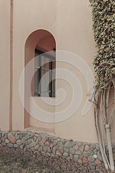 The wall of the building with the arch-shaped window. Minimal boho style in architecture.