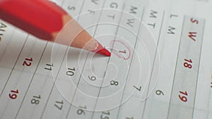 Wall calendar, the number of the month is crossed out. A hand crosses out the days on a paper calendar with a red pen. A