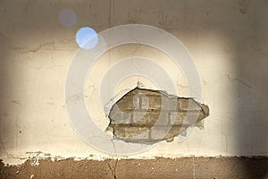 The wall caved in, the plaster and the bricks are visible.