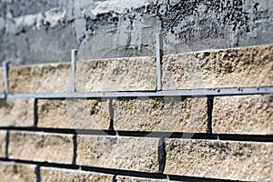 Wall cladding, angle view, process close up. Decorative bricks with rocky relief surface