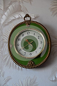 Wall clock in a green rim, decorated with decorative elements