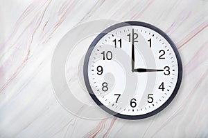 Wall clock show three o`clock on marble texture. Office clock show 3pm or 3am