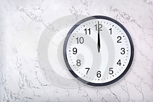 Wall clock show the twelve o`clock on white marble texture. Office clock show midday or midnight