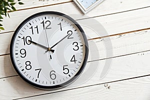 Wall clock showing 2:00 PM on white wooden surface photo