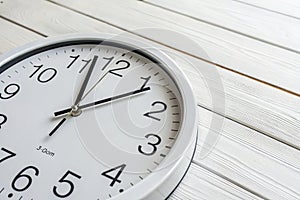 Wall clock showing 2:00 PM on white wooden surface photo