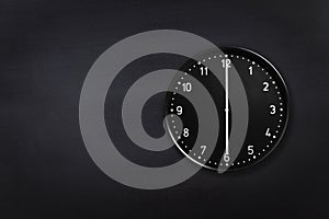 Wall clock showing six o`clock on black chalkboard background. Office clock showing 6am or 6pm on black texture