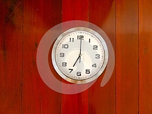 Wall clock at wooden background texture, read at 7 o`clock.