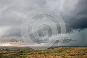 A wall cloud gathers under the base of a supercell storm in the prairie.