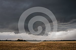 A wall cloud underneath a severe storm over a dry field.