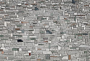 Wall coating made of gray stone bricks arranged arranged with different shapes rock of different colors.