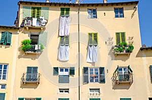 Wall of colorful buildings with shutter windows and drying bed linen on Piazza dell Anfiteatro square of old medieval town Lucca photo