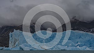 A wall of cracked blue ice rises above a turquoise lake