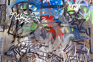 A wall damaged by multicolored paint, graffiti, urban vandalism